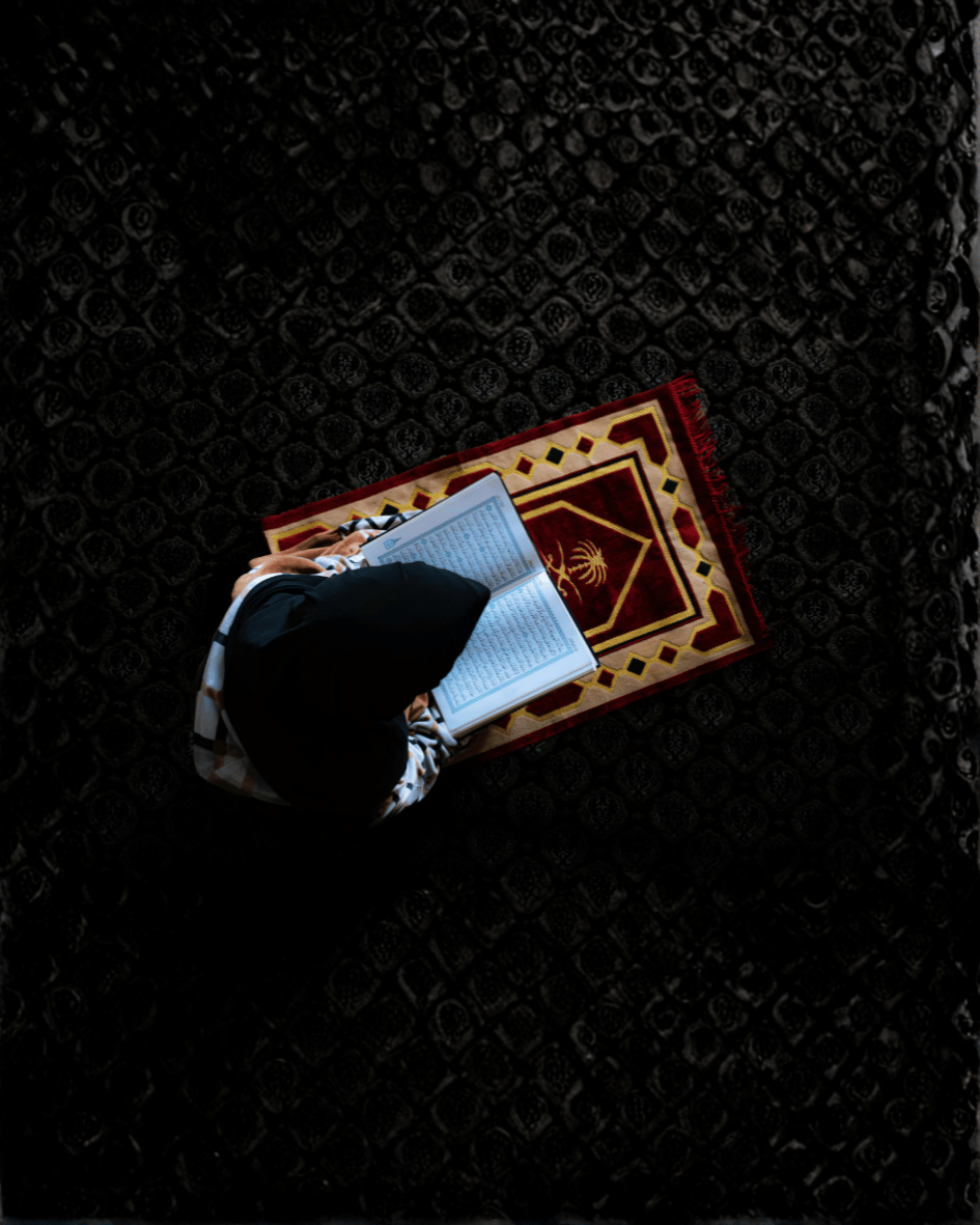 A woman reading the Qur'an on a prayer mat — symbolising spiritual care at the heart of Sherise.